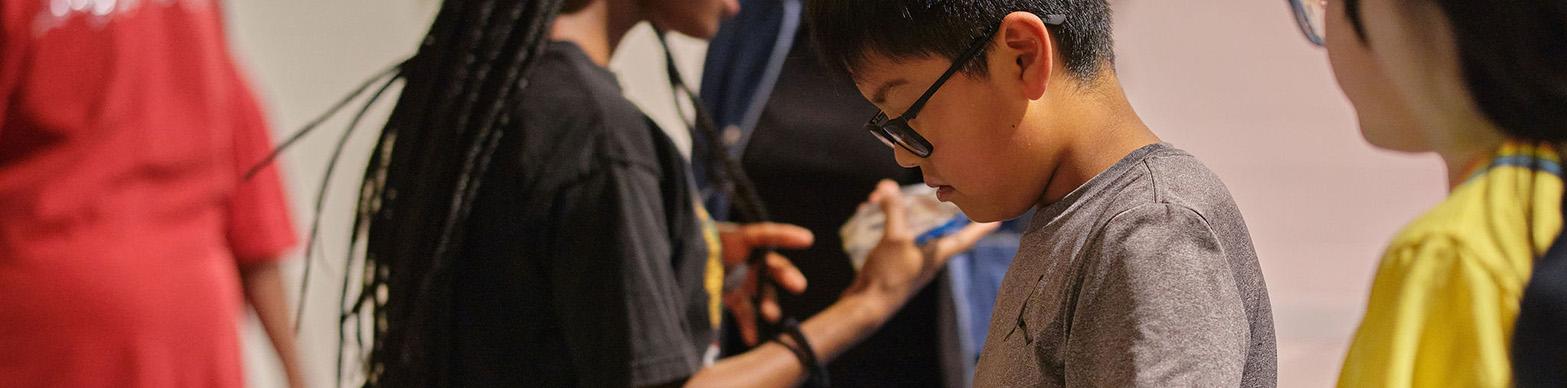 Image of a young asian boy sorting thorugh art supplies